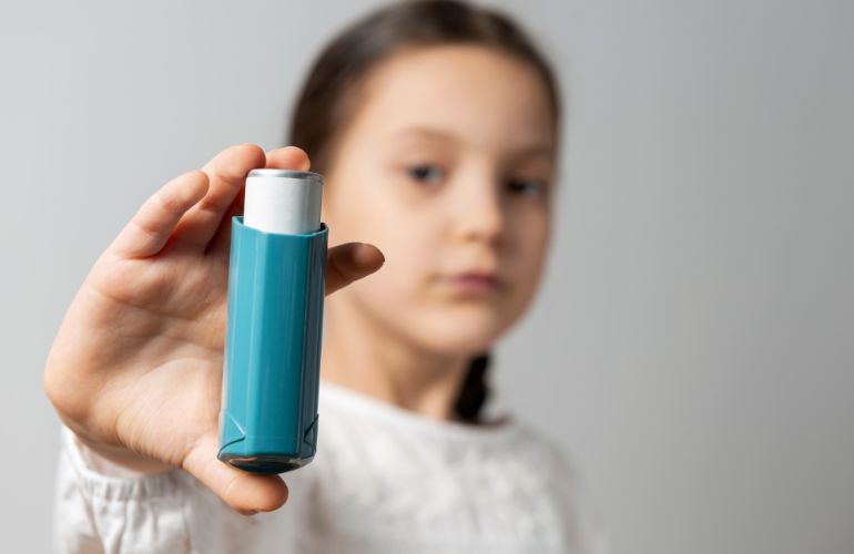 Una niña muestra un inhalador contra el asma.